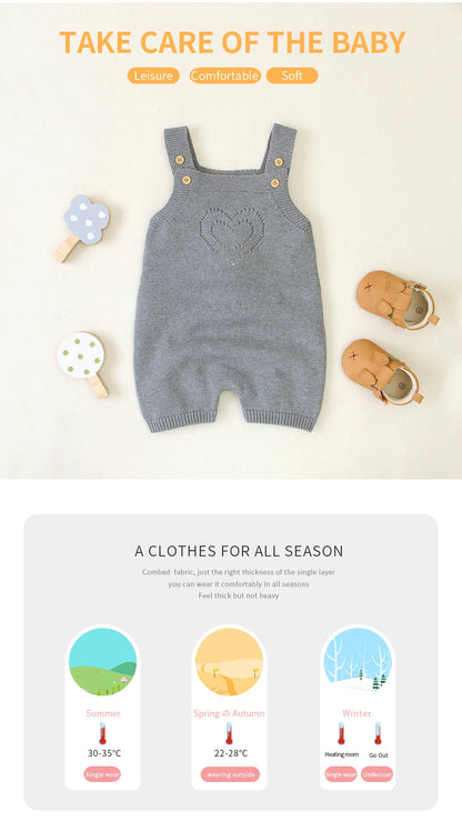 Gray baby romper with heart design on a white background with baby items around.