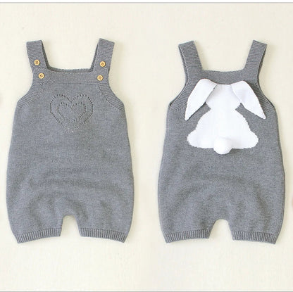 Gray baby romper with heart design and white bear patch on a beige background.